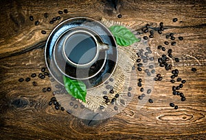 Cup of black coffee with beans on wooden background