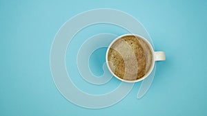 A cup of black coffee on blue background. View from above. copy space