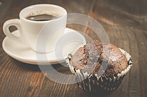 cup of black coffee and a chocolate muffin/cup of black coffee and a chocolate muffin on a dark wooden background. Selective focus