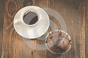 Cup of black coffee and a chocolate muffin/cup of black coffee and a chocolate muffin on a dark wooden background. Top view