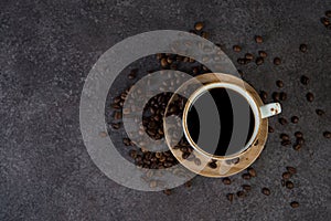 Cup of black coffee with coffee beans around, top view