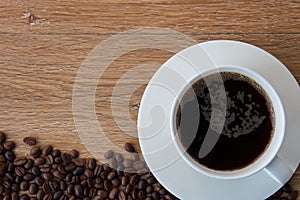Cup of black coffee and coffee beans on wooden background.