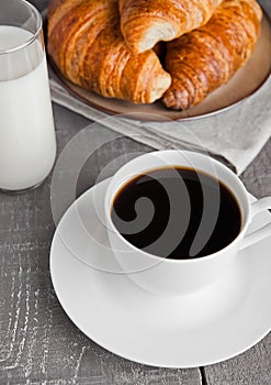 Cup of black coffee and croissant and milk