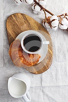 Cup of black coffee with croissant and milk on  table.