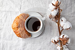 Cup of black coffee with croissant on  table. The concept of breakfast, flat lay, top view