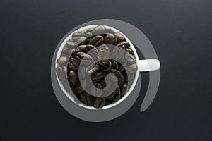 Cup of black coffee with foam on background of roasted coffee beans