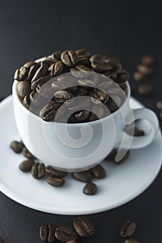 Cup of black coffee with foam on background of roasted coffee beans