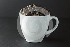 Cup of black coffee with foam on background of roasted coffee beans