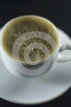 Cup of black coffee with foam on background of roasted coffee beans