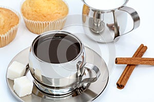 Cup of black coffee with muffin, milk and cinnamon