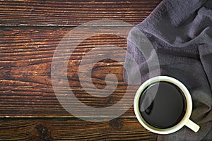 Cup of black coffee  and napkin on old kitchen wooden table.