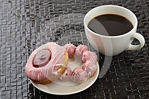 Cup of black coffee with pink donuts