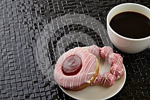 Cup of black coffee with pink donuts