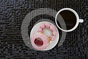 Cup of black coffee with pink donuts