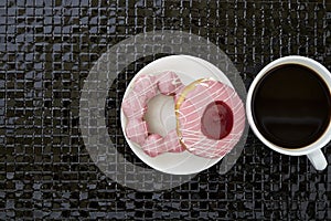 Cup of black coffee with pink donuts