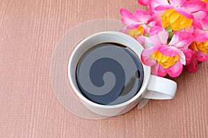 Cup of black coffee and pink flower