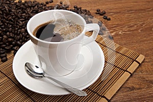 Cup of black coffee with roasted coffe beans