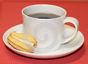 Cup of Black Coffee on Saucer with Biscuit.