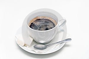 Cup of black coffee on a saucer with a napkin, a teaspoon and lumps of sugar