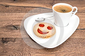 Cup of black coffee with smiled cookie. Funny breakfast