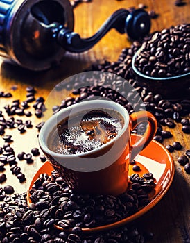 Cup of black coffee and spilled coffee beans.