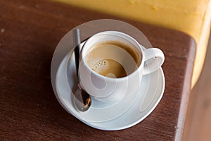 Cup of black coffee with spoon and saucer on table