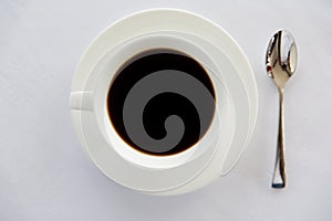 Cup of black coffee with spoon and saucer on table