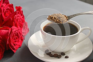 A Cup of black coffee on the table, a bouquet of red roses