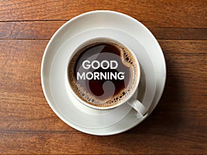 A cup of black coffee with text words Good Morning are written in the foam of the coffee