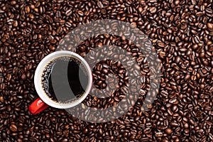 Cup of black coffee from the top on background covered with coffee beans