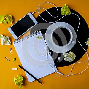 Cup of black coffee on vynil record. Notebook Copy space. Listening to music. Retro style. Mobile phone with headphones