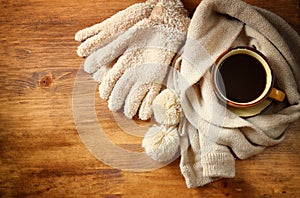 Cup of black coffee with a warm scarf on wooden background. filreted image