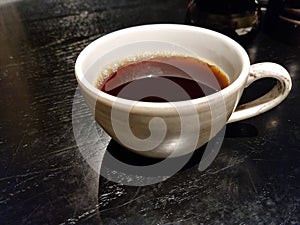 Cup of black coffee in a white mug on a black table closeup photo