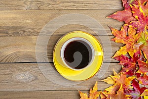 Cup with black coffee on wooden table with autumn fallen yellow, orange and red leaves