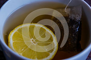 A cup of black strong tea with lemon and tea bag