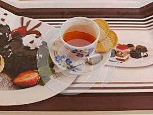 Cup of black tea with biscuits on a tray