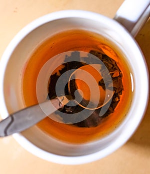 Cup of black tea with brew and spoon top view