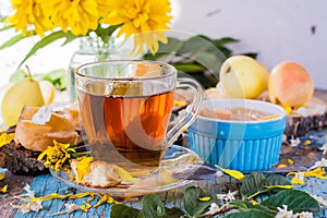 A cup of black tea and jam from pears in a bowl