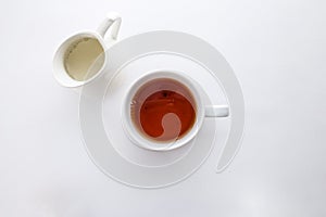 A cup of black tea with and milk jug isolated on white background