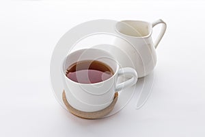 A cup of black tea with and milk jug isolated on white background