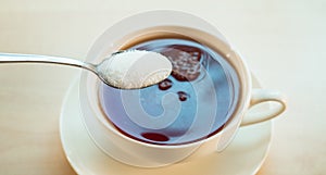 Cup Black tea and spoon with sugar