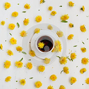 A cup of black tea surrounded by dandelions. Summer tea party. Herbal teas.