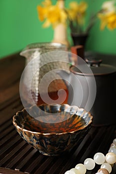 Cup with brewed pu-erh tea and prayer beads on wooden tray, closeup