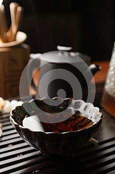 Cup with brewed pu-erh tea on wooden tray, closeup