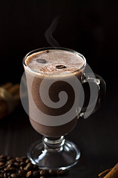 Cup of cacao. glass of hot chocolate with whipped cream, coffee beans and cinnamon sticks on a dark background.