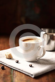 Cup of Cafe Crema and Milk Jug on rustic wooden Background photo