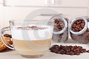 Cup of cappuccino with chocolate crumbs, cookies, and coffee beans on table