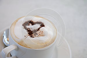Cup of cappuccino with cocoa powder in heart shape on a table in a street cafe, copy space