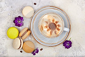 Cup of cappuccino coffee and colorful French dessert macarons