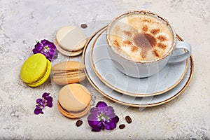 Cup of cappuccino coffee and colorful French dessert macarons